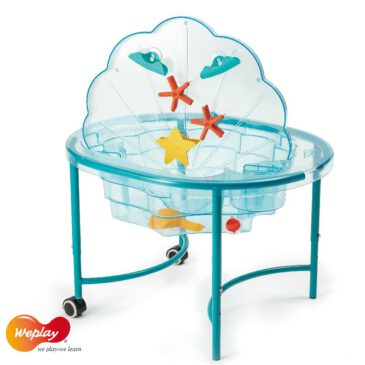 Sand and Water Clam Der indoor Sand- und Wasserspielplatz Die transparente Wanne in Muschelform mit abgestuftem Rand ermöglicht es bis zu sechs Kindern mit Wasser in verschiedenen Tiefen zu spielen und dabei sensorische Erfahrungen zu sammeln. Der Deckel kann senkrecht in die Wanne gestellt und die verschiedenen Wasserspielzeuge mit Saugnäpfen daran befestigt werden. Die beiden runden Fächer am Wannenrand dienen zur Aufbewahrung des Zubehörs und erleichtern das Öffnen und Schließen des Deckels. Im Gestell unter der Wanne platziert dient der Deckel als Ablagefläche. Trichter, Wasserräder und Rinnen ermöglichen es, den Wasserfluss zu variieren. Beim Spielen damit lernen die Kinder zu kommunizieren und mit Gleichaltrigen zu teilen. Durch eine Öffnung am Boden wird das Wasser nach Gebrauch einfach abgelassen. Alternativ kann die muschelförmige Wanne auch mit Sand gefüllt werden, um den Kindern abwechslungsreiche Sinneserfahrungen zu bieten.