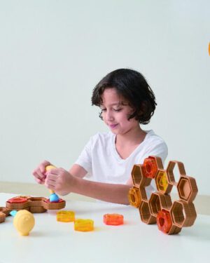 Squeezy Bee Blocks Auf die Plätze ... fertig - drücken! Ziel dieses Feinmotorik-Spiels ist es die transparenten Honey Blocks (Honigblöcke) mit dem Bee Squeezers (Bienenquetscher) in den Bienenstock reinzuschieben. Bzw. wenn er aufgestellt ist ohne, dass sie hinten wieder herausfallen. Inhalt: 2x Bienenquetscher, 8x Bienenstockrahmen, 12x Honigblöcke (6 gelb, 6 orange), 2 x Standfüße, 30x Ballon, 6x doppelseitige Aktivitätskarten. Produktmerkmale: • Die Verwendung des Bee Squeezers, um Honey Blocks zurück in den Bienenstockrahmen zu bewegen, fördert die Hand-Augen-Koordination. Außerdem verbessert es die Vorausplanung von Handlungen und die Aufrechterhaltung der Muskelkraft. • Der Bee Squeezer ist ein lustiges Spielzeug, mit dem man die Greifkraft der Hände trainieren kann. Der Bee Squeezer bläst einen Ballon auf, der die tropfenförmige Mitte der Honigblöcke ausfüllt. • Die beiden Enden des Bee Squeezers haben unterschiedliche Funktionen. Mit dem vorderen Ende des Bee Squeezers wird der Ballon durch Drücken aufgepumpt und wieder entleert. Das hintere Ende des Bee Squeezers kann in die Honey Blocks eingeführt werden, was für jüngere Kinder oder Kinder mit schwacher Greifkraft für grundlegende Übungen geeignet ist. • Der Bienenstockrahmen kann so platziert werden, dass er eine Vielzahl unregelmäßiger Formen bildet oder gestapelt wird, um Bienenstöcke unterschiedlicher Tiefe zu bauen. • Mit zusätzlichen Standfüßen, die ihn in einen aufrechten Bienenstockrahmen verwandeln, müssen Kinder nicht nur überlegen, wie sie die Struktur stabiler machen können, sondern auch, wie sie die Kraft beim Tragen und Zurückschieben der Honigblöcke in den Bienenstockrahmen dosieren können. • Transparente Honigblöcke mit unterschiedlichen haptischen Mustern, kombiniert mit einem soliden und einem transparenten Bienenstockrahmen, werten die Optik des Weplay Squiz Squiz Sweet deutlich auf.